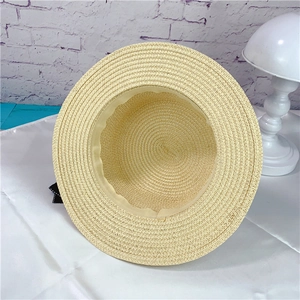 Detail view of woven straw hat interior featuring a light sweatband and black bow accent