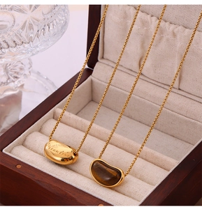 Détail du pendentif en pierre œil de tigre et pendentif gravé dream love sur chaîne dorée
