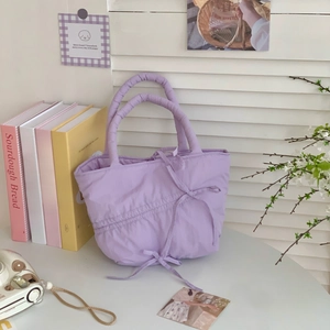 Detail of light purple pleated tote bag showing quilted texture and ribbon decoration