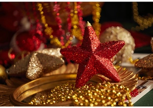 Macro shot of red glitter star ornaments and golden bead chains in a festive setting