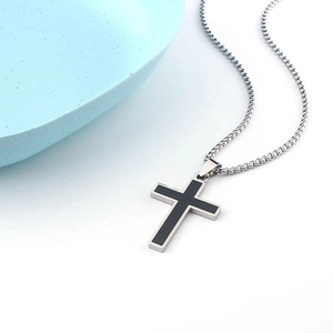 Close-up of black cross pendant with silver metal frame and square box chain necklace