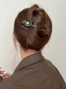 Detail of dark translucent resin swallowtail hair clip with golden fashion decoration