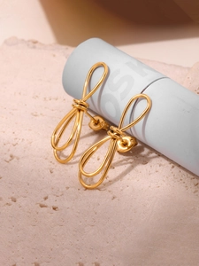 Détail de boucles d'oreilles nœuds dorés sur support en pierre avec lumière douce