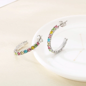 Dettaglio orecchini a cerchio C in argento con zirconi colorati su piatto bianco