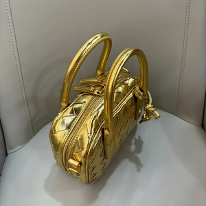 Close-up of golden woven texture mini handbag on grey leather seat with dual handles