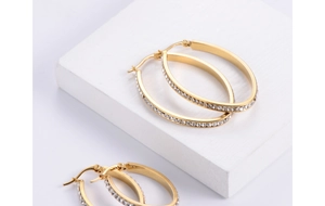 Detail of gold oval hoop earrings with sparkling rhinestones and polished finish