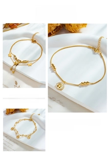 Detailed close-up of layered gold stainless steel anklets with butterfly and tree of life charms