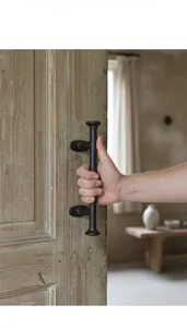 Close-up of vintage black cast iron door handle with textured finish on weathered wood