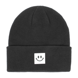 Dettaglio di un berretto in maglia nero con etichetta quadrata e icona smile