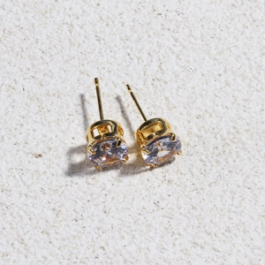Close-up of classic 4-prong round zircon stud earrings with gold plating on stone base