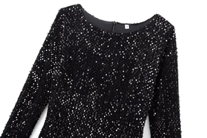 Détail d'une robe noire à paillettes montrant le col rond et la texture du tissu brillant
