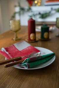 Close-up of festive red and green Christmas placemat set with elegant wooden cutlery