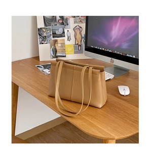 Detail of khaki leather tote bag on a modern office desk with workspace accessories