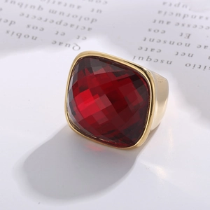 Detail view of a vintage gold-plated wide band ring with a faceted red crystal stone