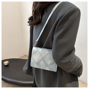 Close-up of a light blue quilted crossbody bag featuring elegant gold chain details