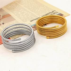 Detail of spiral spring bangle bracelets in gold and silver finish on newspaper