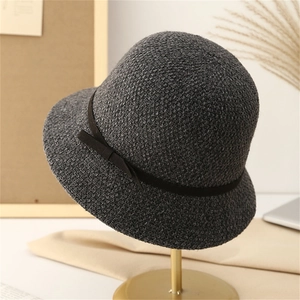 Close-up of dark grey knitted cloche hat with a delicate black bow on a gold stand