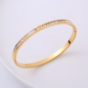 Close-up of gold bangle with white mother-of-pearl inlay and sparkling cubic zirconia stones