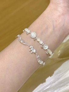 Vue détaillée de bracelets en argent avec marguerite, perles et nœud en zircon au poignet