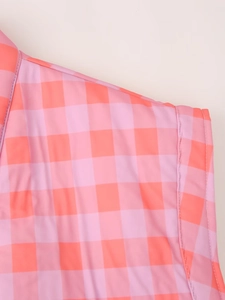 Detail view of pink and orange plaid pattern fabric on sleeveless vest shoulder