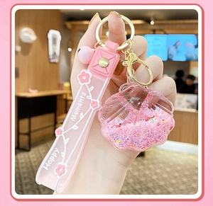 Detailed close-up of pink shell-shaped quicksand keychain with Happy Moments strap