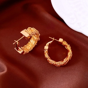 Macro shot of 24k gold plated earrings with woven texture on dark brown silk fabric