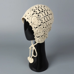 Gros plan du bonnet au crochet fait main crème avec motifs floraux ajourés et pompons