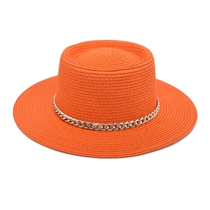 Detail of bright orange straw boater hat with a decorative silver metal chain band