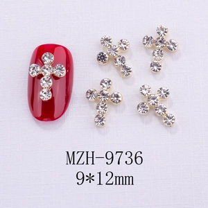 Dettaglio macro di ciondoli a croce dorati 9x12mm con strass su nail art rossa lucida