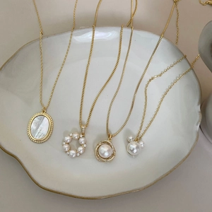 French baroque pearl necklace with oval shell pendants on a ceramic tray display