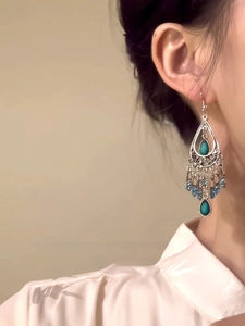 Close-up of bohemian blue teardrop tassel earrings with silver metal and layered beadwork