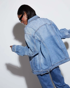 Rear view of loose fit washed denim jacket for women in light blue with premium stitching