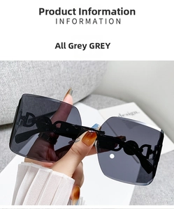 Close-up of frameless oversized grey sunglasses featuring metallic letter temple detail