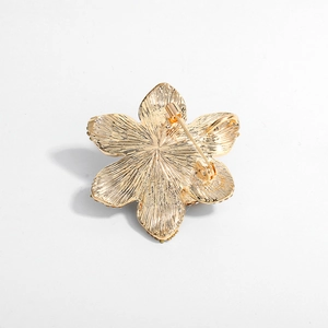 Golden flower brooch with pin and necklace loop back view on white background
