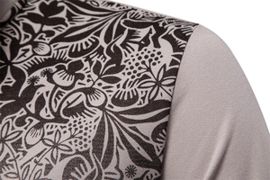 Detailed view of the shoulder stitching on khaki polo shirt with dark botanical prints