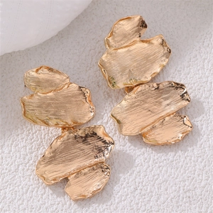 Macro shot of irregular golden leaf earrings with hammered metal texture detail