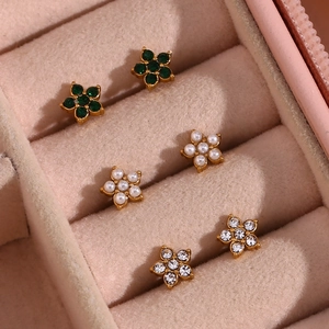 Gros plan détaillé de trois paires de puces d'oreilles fleurs dans une boîte à bijoux