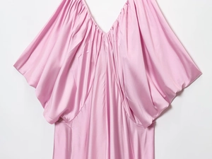 Detailed view of pink satin dress featuring deep V-neck pleats and draped oversized sleeves