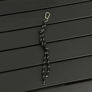 Close-up of black braided paracord lanyard with reflective dots and metal carabiner hook