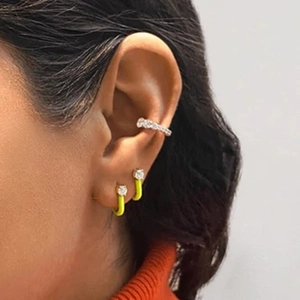 Detail of neon yellow rhinestone hoop earrings and silver ear cuff on model