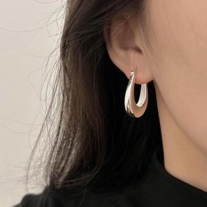Macro view of minimalist silver U-shaped hoop earring worn on a female model