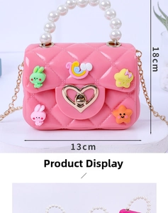 Close-up of pink mini jelly bag with pearl handle, cute cartoon charms and gold chain strap