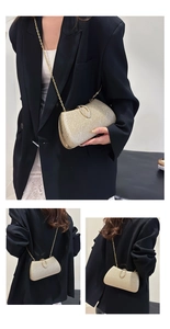 Close-up of elegant gold glitter chain bag with metallic clasp worn with black blazer