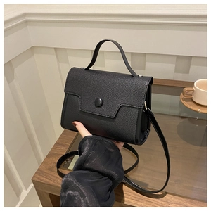 Close-up of black pebble grain leather texture on a minimalist crossbody handbag