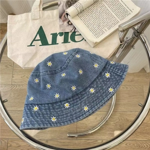 Denim bucket hat with daisy embroidery on a glass table with aesthetic props