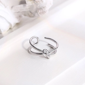 Minimalist silver-colored knotted metal ring with an open-end design in macro detail