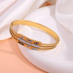 Close-up of a gold triple-layer evil eye bracelet with crystals on white silk background