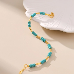 Close-up of turquoise beads and 18K gold plated tubes on a bohemian summer bracelet