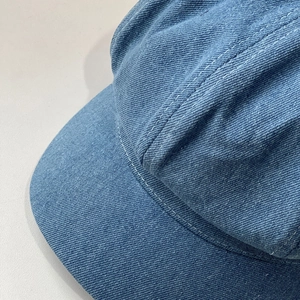 Close-up of blue denim newsboy hat showing detailed stitching and twill fabric texture