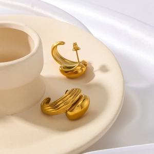 Golden C-shaped stainless steel earrings with textured and smooth finishes on silk